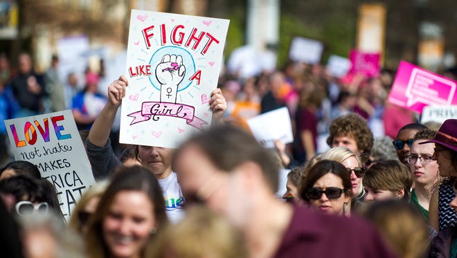 Signs are held as marchers make their way down Andy Holt Avenue during the University of Tennessee's "sister march" to the Women's March on Washington on Friday, January 20, 2017.
