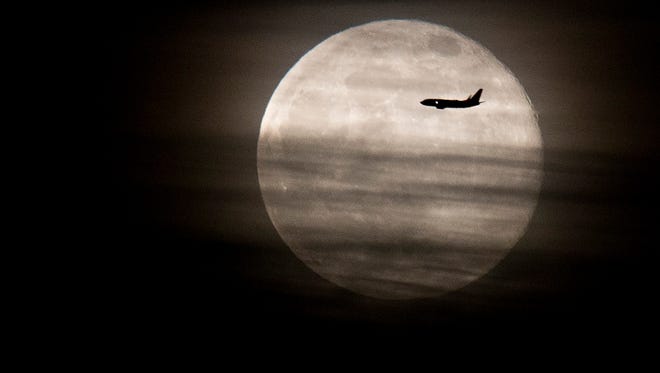 An airplane is silhouetted against the 'Super Moon' as it makes it's way from Sky Harbor Airport Sunday, June 23, 2013.