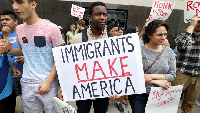 En esta imagen tomada el 16 de mayo de 2017, Torianto Johnson, estudiante de primer año en Pioneer High School en Ann Arbor, Michigan, sostiene un cartel en favor de los inmigrantes que dice: “los inmigrantes hacen grande a América”, durante una protesta en el exterior de una corte federal en Detroit.