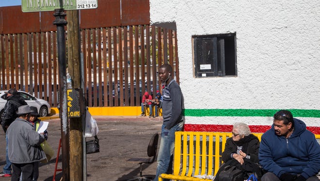 A Haitian migrant stands near the border fence in Nogales, Sonora, where the streets of Nogales, Arizona, can be seen through the slats. Between 200 and 250 Haitian migrants have arrived in this border city since October, hoping to cross through the port of entry into the U.S. without American visas.