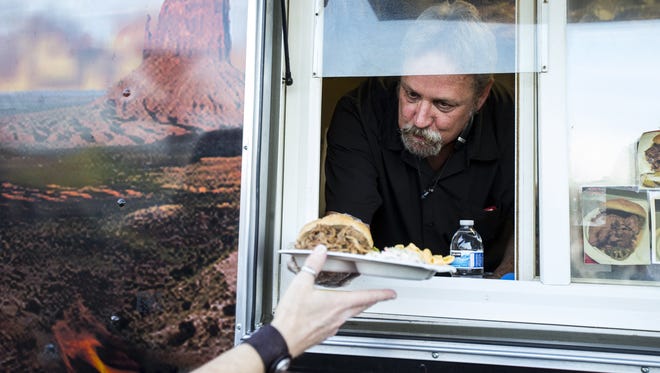 Rep. Kevin Payne hands a customer her order at his K Star BBQ food truck on Friday, Feb. 2, 2018 in Glendale, Ariz. Payne has proposed a bill that would remove several regulations for food trucks.
