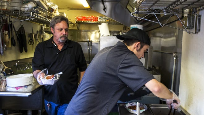 Rep. Kevin Payne (left) and Daniel Drake prepare food in Payne's K Star BBQ food truck on Friday, Feb. 2, 2018 in Glendale, Ariz. Payne has proposed a bill that would remove several regulations for food trucks.