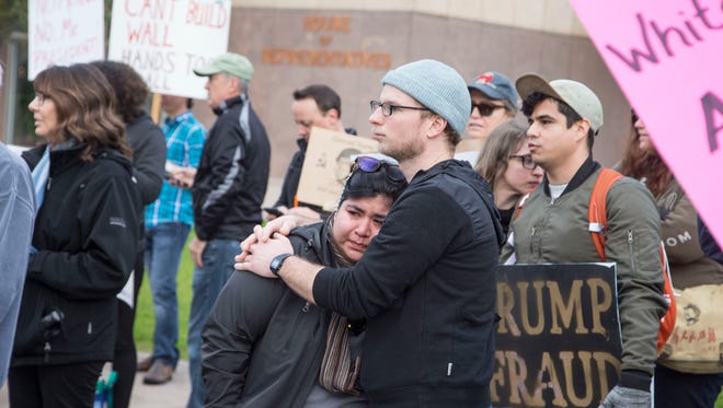 Eric Merrill hugs Alex Araiza, who says she was  there to non-violently resist hatred, as several hundred people protest at the Arizona state Capitol during the inauguration of Donald Trump as president of the United States on Jan. 20, 2017.