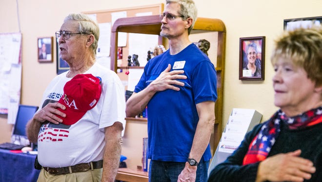 Tom Scanlan (left), 78, Sun City, holds his "Make America Great Again" hat over his heart during the national anthem as he and other Donald Trump supporters at the Arizona Republican Party office in Sun City watch the inauguration of the 45th president of the United States via a live television feed.