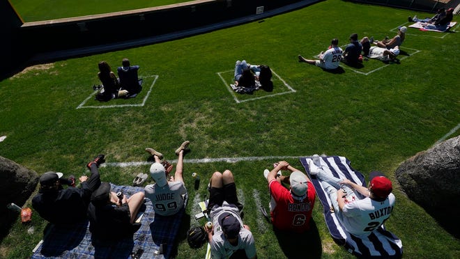 Fans sit in their COVID-19 socially-distanced pods at the Goodyear Ballpark during the fourth inning of a spring training baseball game between the Cleveland Indians and the Cincinnati Reds on Sunday, Feb. 28, 2021, in Goodyear, Ariz.