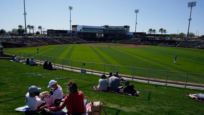 Fans sit in their COVID-19 social-distancing pods at the Goodyear Ballpark during the fourth inning of a spring training baseball game between the Cleveland Indians and the Cincinnati Reds on Sunday, Feb. 28, 2021, in Goodyear, Ariz.