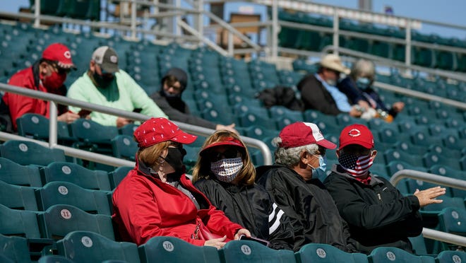 A limited number of mask-wearing fans wait for the start of a spring training baseball game between the Cleveland Indians and the Cincinnati Reds at Goodyear Ballpark on Sunday, Feb. 28, 2021, in Goodyear, Ariz.
