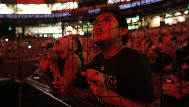 Joseph White watches fireworks through the netting behind homeplate in Chase field. A 15-minute fireworks display in Chase Field followed the Arizona Diamondbacks game on Saturday night.