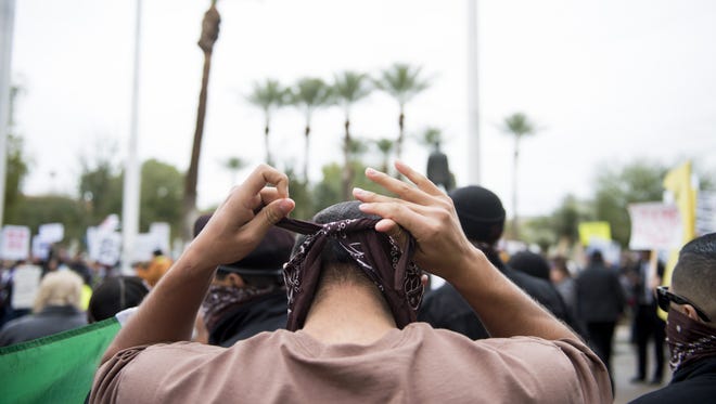 A demonstrator ties a bandanna around his face during a protest against the inauguration of Donald Trump as the 45th president of the United States at the Arizona state Capitol in Phoenix on Jan. 20, 2017. Trump's election to the presidency has sparked protests since Election Day.