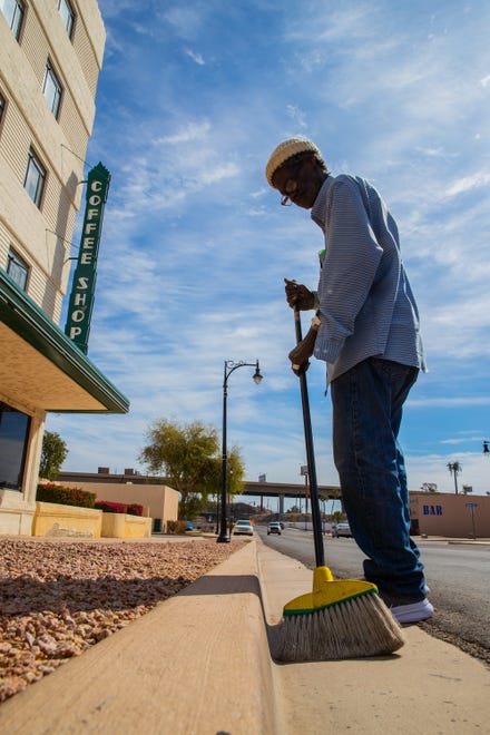 Willie Robinson, 66, sweeps the curb outside Hotel San Carlos, as is routine for him, in Yuma on March 16, 2023. Robinson, who has lived at the Hotel San Carlos affordable apartments for about five years, said his case manager took him to his future apartment, which is larger than his current one and comes with a TV. He said he's excited to move into a bigger place.