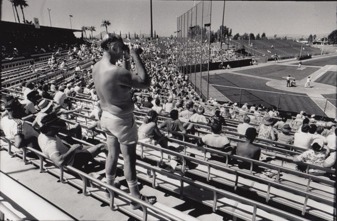 A fan watches the game through binoculars during an Iowa Cubs and North Carolina Knights game during spring training March 19, 1990.