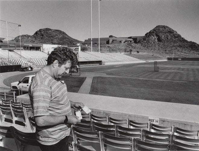 A fan stands in a stadium looking at his game tickets during spring training March 19, 1990.