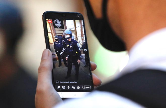 Un manifestante utiliza su teléfono celular para grabar actividad policial el viernes 11 de septiembre de 2020 durante protestas contra brutalidad policial.