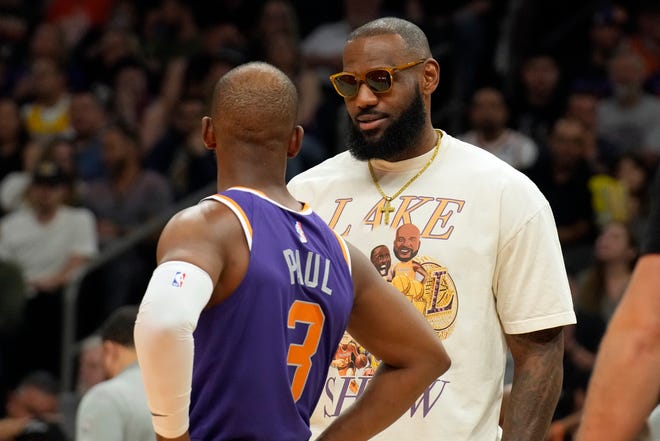 La estrella de los Lakers de Los Ángeles, LeBron James, habla con el escolta de los Suns de Phoenix, Chris Paul (3), durante la primera mitad de un partido de baloncesto de la NBA, el martes 5 de abril de 2022, en Phoenix.