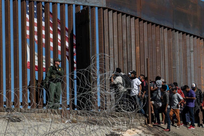 Migrantes centroamericanos miran a través de una valla fronteriza mientras un agente de la Patrulla Fronteriza de Estados Unidos hace guardia cerca del cruce fronterizo de El Chaparral en Tijuana, México, el 25 de noviembre de 2018.