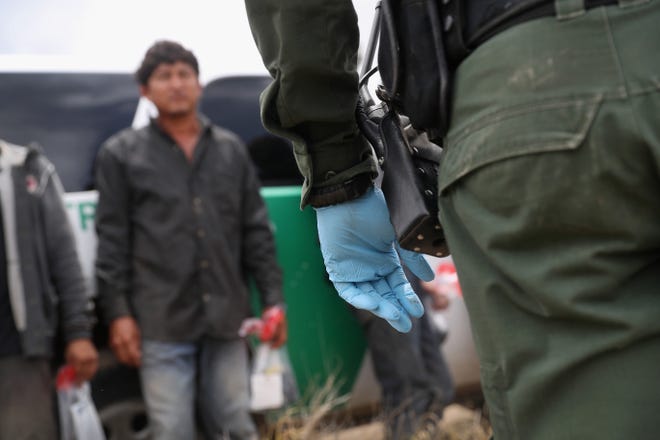 Un agente de la patrulla fronteriza detiene a un grupo de migrantes en Texas.