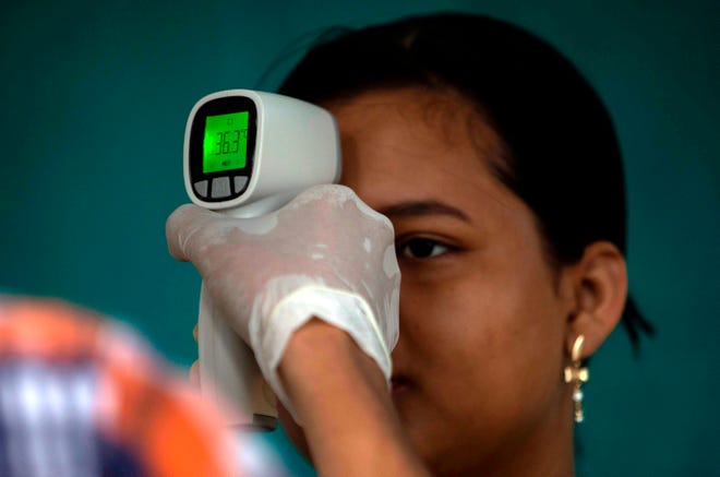 Una mujer se toma la temperatura, en un punto de inspeccion anti-coronavirus en Guatemala.
