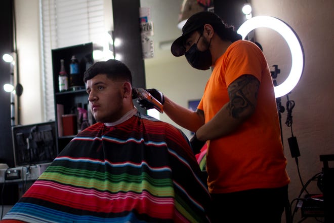 Jon Hern á ndez (derecha) corta el cabello de Edgar Villa (izquierda) en Fay ' s barber í a en Phoenix, Arizona, el 11 de mayo de 2020. Despu é s de que el gobernador de Arizona, Doug Ducey, permitiera que los salones, barber í as y otras tiendas minoristas reanudaran sus negocios, comenzaron muchas barber í as y salones en Phoenix teniendo clientes solo con cita previa.