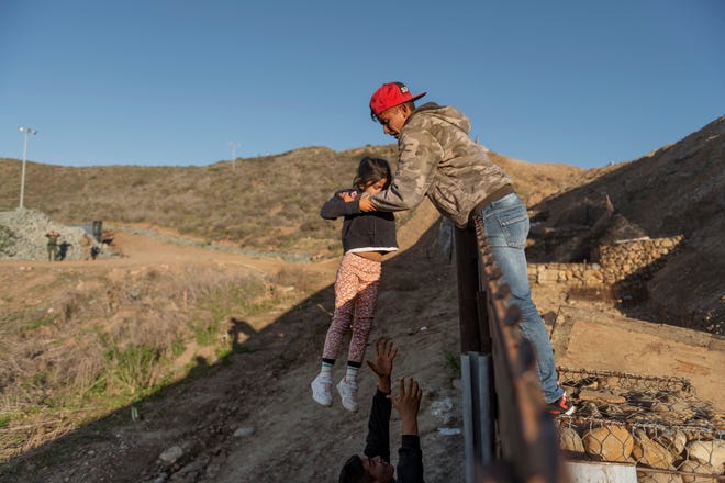 En esta foto de archivo se observa a un migrante al momento de cruzar a una niña del otro lado de la cerca, en la frontera de Tijuana-San Diego.