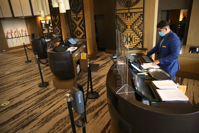 Manager Andrew Castillo works the front desk behind social distancing barriers at the Phoenician Aug 18, 2020. The resort has made changes in response to the COVID-19 outbreak.