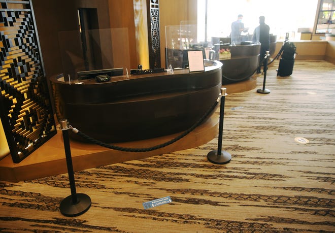 A guest is helped at the front desk as plexiglass and social distance barriers can be seen at the Phoenician Aug 18, 2020. The resort has made changes in response to the COVID-19 outbreak.