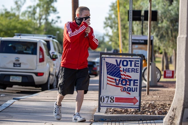 Un votante se cubre la cara antes de ingresar al lugar de votación de la Biblioteca Himmel Park en Tucson el 3 de noviembre de 2020.