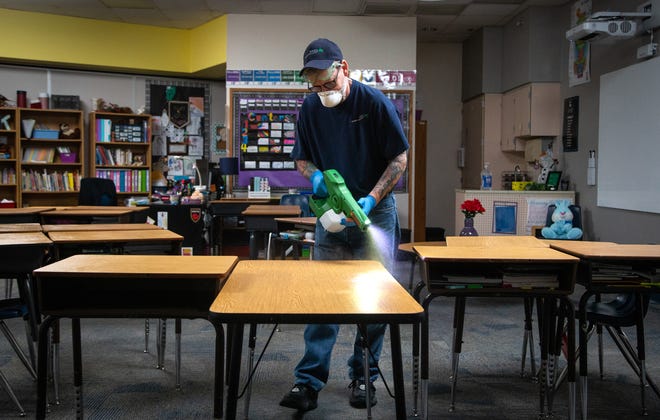 Robert Truman, with SSC Services for Education, uses an electrostatic sprayer to sanitize a classroom, March 12, 2020, at Kyrene de la Mirada Elementary School in Chandler, Arizona.