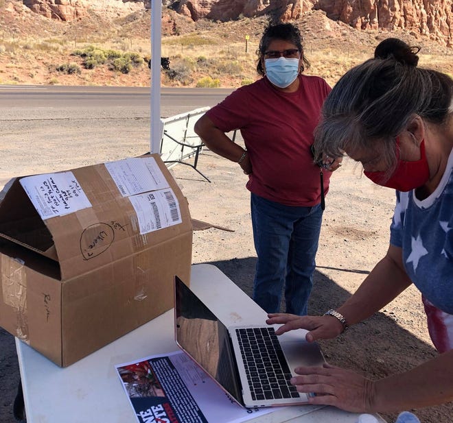 Native Vote Campaign Coordinator Patricia Nezzie (right) checks the voter status and the polling location for a voter on the Navajo Nation.