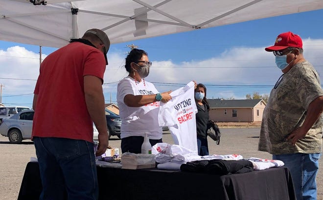 ​Volunteers with the nonprofit organization Diné C.A.R.E. (Citizens Against Ruining Our Environment) talk with Navajo Nation voters at the Dilkon Chapter House in Dilkon, Arizona, on Election Day in 2020.
