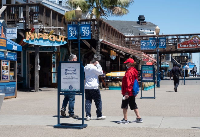 Un trabajador recuerda a los clientes que usen una máscara protectora en Pier 39, un popular centro comercial y atracción turística en San Francisco, California.