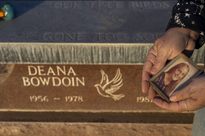 Leslie Bowdoin James visits her sister Deana Bowdoin's gravesite and holds a picture of her at Greenwood Memory Lawn Mortuary and Cemetery in Phoenix on Jan. 14, 2021.