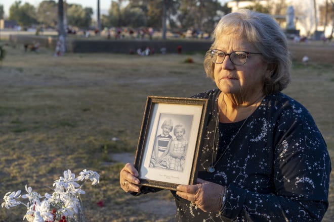 Leslie Bowdoin James holds a photo of her and her sister, Deana Bowdoin, at her gravesite at Greenwood Memory Lawn Mortuary and Cemetery in Phoenix on Jan. 14, 2021.