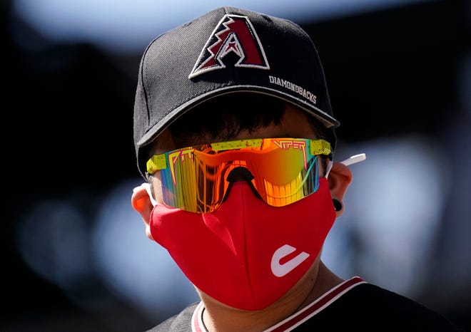 A masked fan watches the Arizona Diamondbacks play the Colorado Rockies during the spring training opener at Salt River Fields at Talking Stick in Scottsdale, Ariz., on Feb. 28, 2021.