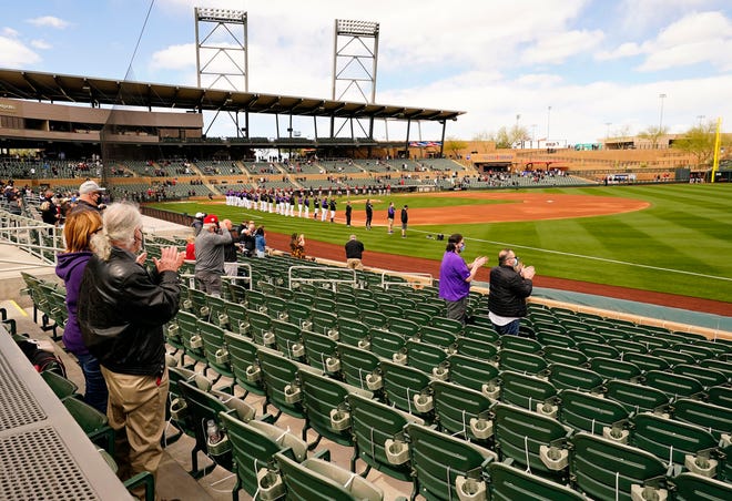 Socially distanced fans stand for the national anthem during the spring training opener as the Colorado Rockies host the Arizona Diamondbacks at Salt River Fields at Talking Stick in Scottsdale, Ariz., on Feb. 28, 2021.