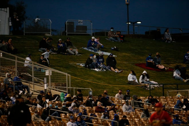 Fans watch from designated boxes in the lawn during the second inning of the MLB Cactus League Spring Training game between the Los Angeles Dodgers and the Cincinnati Reds at Camelback Ranch in Glendale, Ariz., on Wednesday, March 3, 2021. The game, scheduled for seven innings, was tied at 2 in the fifth inning.