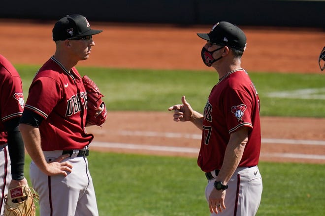 Arizona Diamondbacks pitcher Taylor Widener, left, talks with manager Torey Lovullo during the fourth inning of a spring training baseball game against the Cleveland Indians on Wednesday, March 3, 2021, in Goodyear, Ariz.