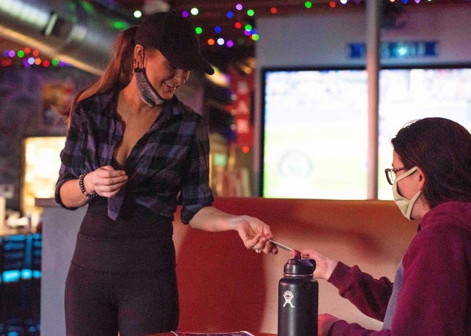 Bartender Lindsay Hemeon serves customers at The Bar in Phoenix hours after Gov. Doug Ducey lifts all COVID-19 restrictions from bars and restaurants on March 25, 2021.