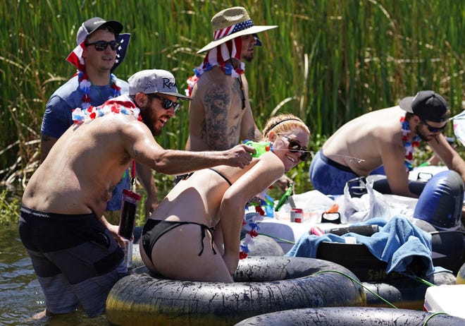 Brandon Richardson, 31, and Tiffany McCarthy, 27, of Tucson, play with squirt guns while tubing at the Salt River on May 29, 2021.