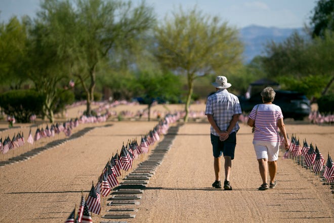 A couple walks past gravestones and flags on Memorial Day at the National Memorial Cemetery of Arizona in Phoenix on May 31, 2021.