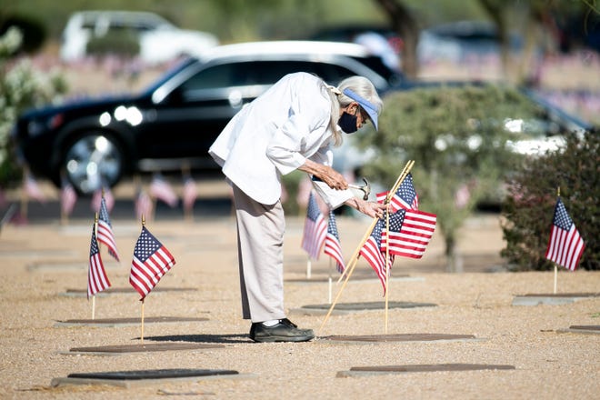 Ida Coke places flags at the National Memorial Cemetery of Arizona on Memorial Day in Phoenix on May 31, 2021. Her husband was buried a few feet away nearly 26 years ago.