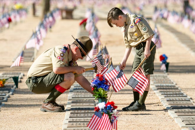 David Marquardt (left) hammers a flag into a grave with the help of his son, Liam Marquardt, 11, (right) at the National Memorial Cemetery of Arizona in Phoenix on May 31, 2021.