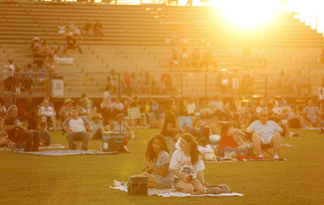 People arrive and stake out their spots in the grass at Apache Junction's Fourth of July fireworks at Apache Junction High School on July 4, 2021.