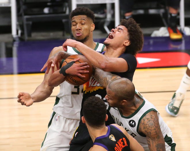Phoenix Suns forward Cameron Johnson (23) comes down with a rebound between Milwaukee Bucks forwards Giannis Antetokounmpo (34) and P.J. Tucker (17) during Game 2 of the NBA Finals at Phoenix Suns Arena July 8, 2021.
