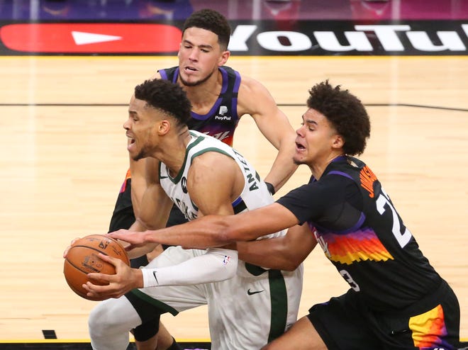 Milwaukee Bucks forward Giannis Antetokounmpo (34) is defended by Phoenix Suns guard Devin Booker (1) and forward Cameron Johnson (23) during Game 2 of the NBA Finals at Phoenix Suns Arena July 8, 2021.