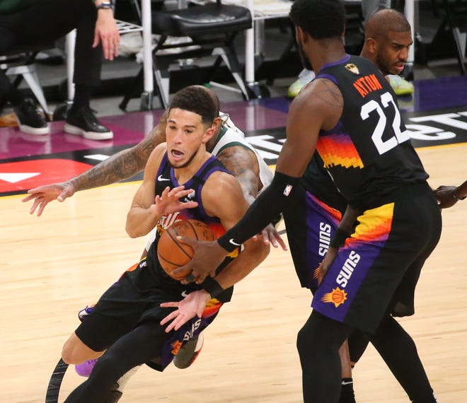 Phoenix Suns center Deandre Ayton (22) hands the ball off to Phoenix Suns guard Devin Booker (1) against the Milwaukee Bucks during Game 2 of the NBA Finals at Phoenix Suns Arena July 8, 2021.