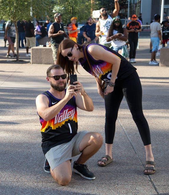 Nichole Uribe looks down as Ryan Gorczyca takes a photo of Suns fans before Game 2 of the NBA Finals outside the Phoenix Suns Arena on July 8, 2021.