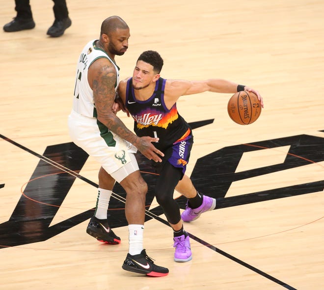 Phoenix Suns guard Devin Booker (1) is defended by Milwaukee Bucks forward P.J. Tucker (17) during Game 2 of the NBA Finals at Phoenix Suns Arena July 8, 2021.