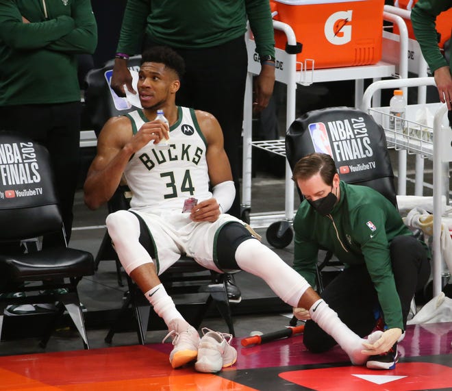 Milwaukee Bucks forward Giannis Antetokounmpo (34) has his leg worked on during Game 2 of the NBA Finals against the Phoenix Suns at Phoenix Suns Arena July 8, 2021.