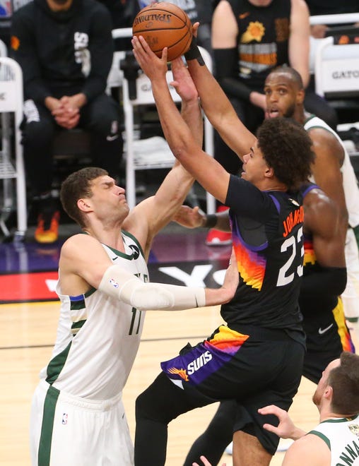 Phoenix Suns forward Cameron Johnson (23) is fouled by Milwaukee Bucks center Brook Lopez (11) during Game 2 of the NBA Finals at Phoenix Suns Arena July 8, 2021.