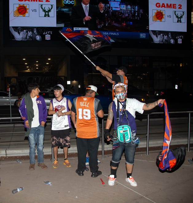 Elias Narjera, front, and Victor Varona, back, hold LOS SUNS flags to celebrate after the Suns beat the Milwaukee Bucks 118-108 in Game 2 of the NBA Finals outside the Phoenix Suns Arena in Phoenix on July 8, 2021.